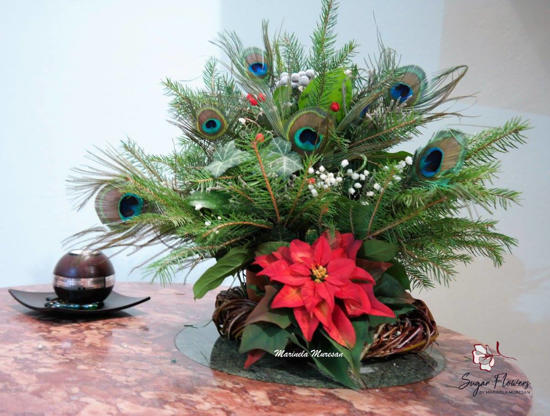 O craciunita din zahar, alaturi de un aranjament din crengi si frunze naturale, plus cateva pene de paun.