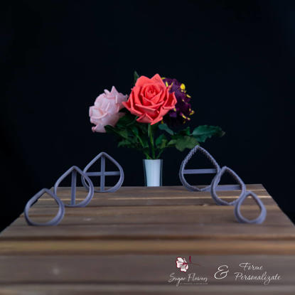 Decupatoare gri asezate pe o masa langa un Trandafir de culoare visiniu cu galben